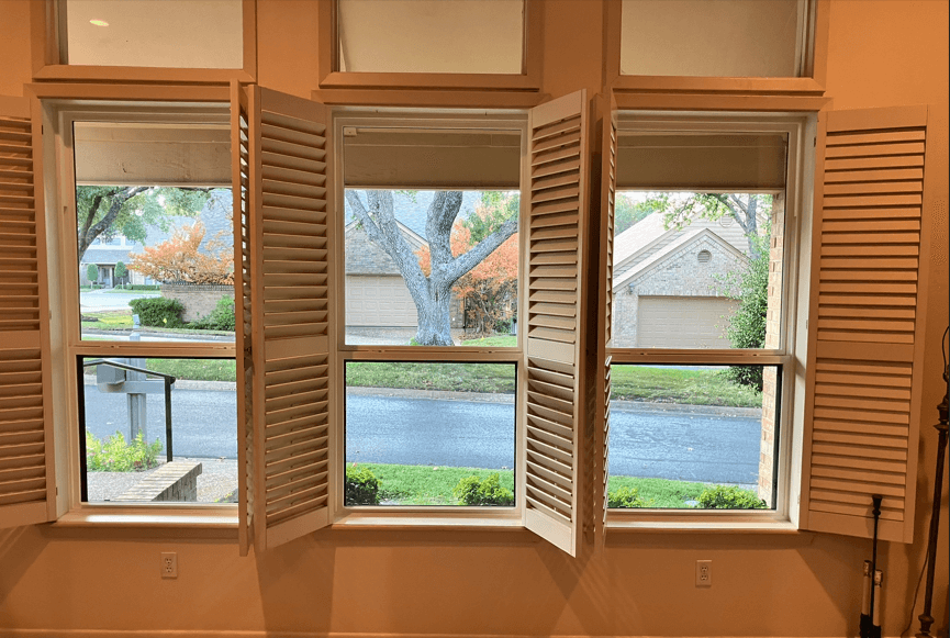 3 cream color, interior home windows with shutters open overlooking green lawn and neighborhood