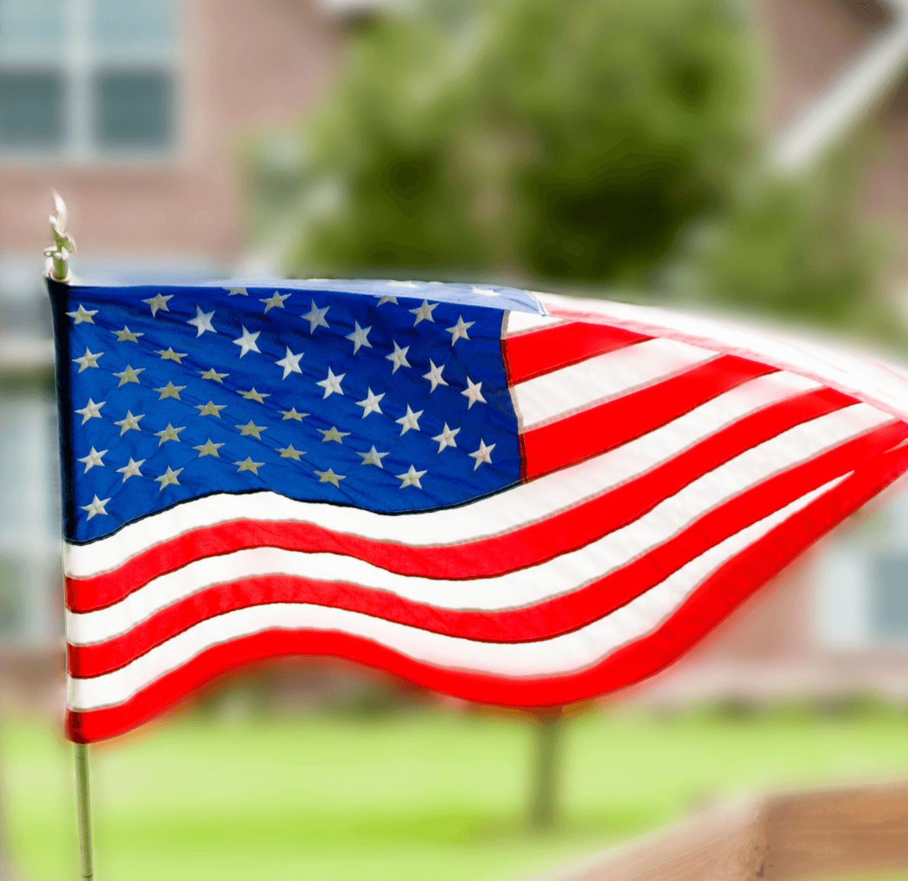 American flag blowing in front of brick home