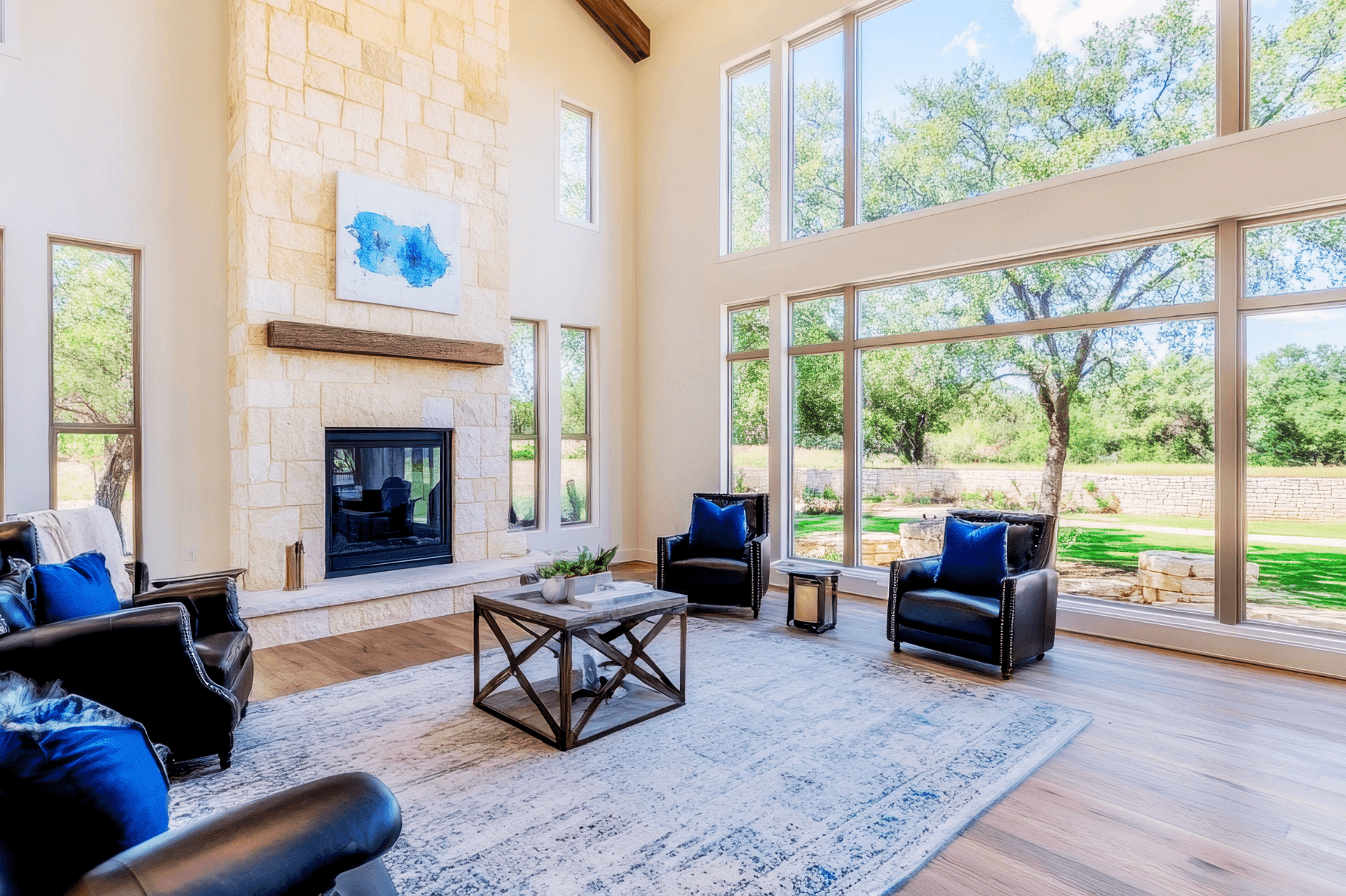 sunny home living room with high rock walls, fireplace and floor to ceiling windows