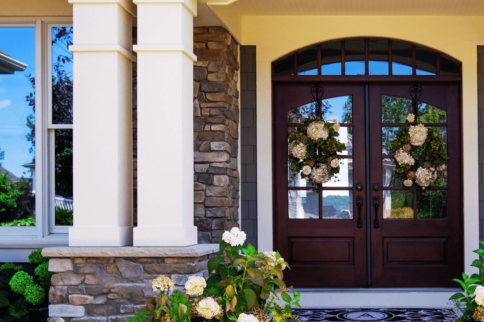 large double wood front entry doors, white rose and rock siding