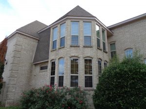 A set of multiple long windows sitting on the side of a brick home