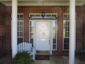 A white door with gold accents at the front entrance of a brick home.