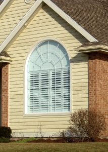 arched house window on a newly constructed home with yellow siding