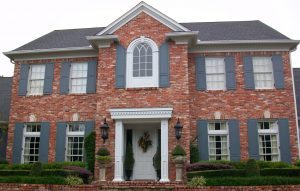 Grand symmetrical brick front house with windows above the entry door and on either side