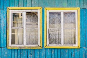 close up of old wooden windows surrounded by bright blue wood siding